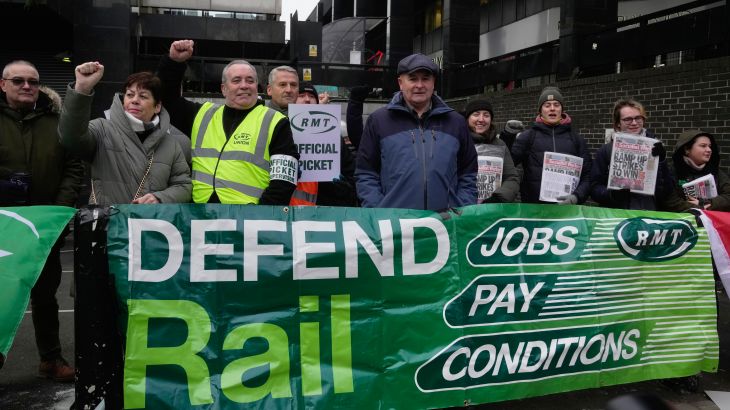 Mick Lynch, general secretary of the Rail, Maritime and Transport union (RMT), center, joins the members of rail workers during a strike outside Euston station in London, Tuesday, Dec. 13, 2022. (AP Photo/Kin Cheung)