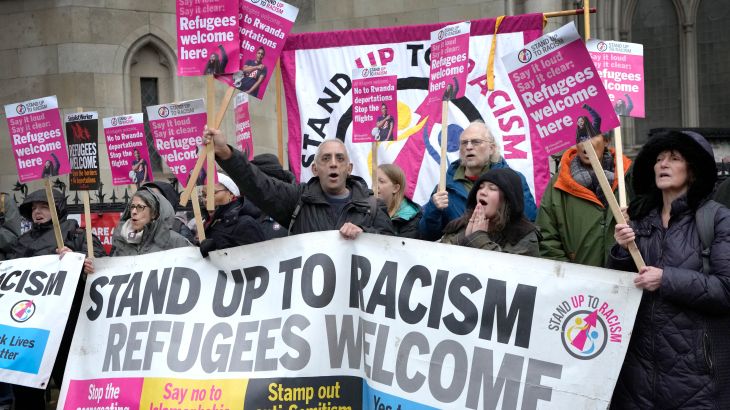 Stand Up To Racism campaigners hold banners outside the High Court in London