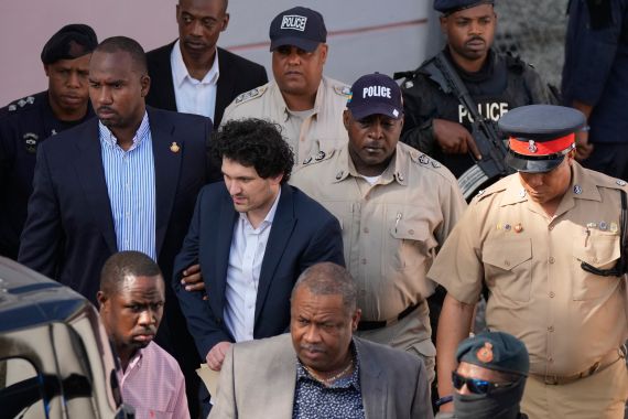 FTX founder Sam Bankman-Fried, center left, is escorted out of Magistrate Court into a Corrections van, following a hearing in Nassau, Bahamas
