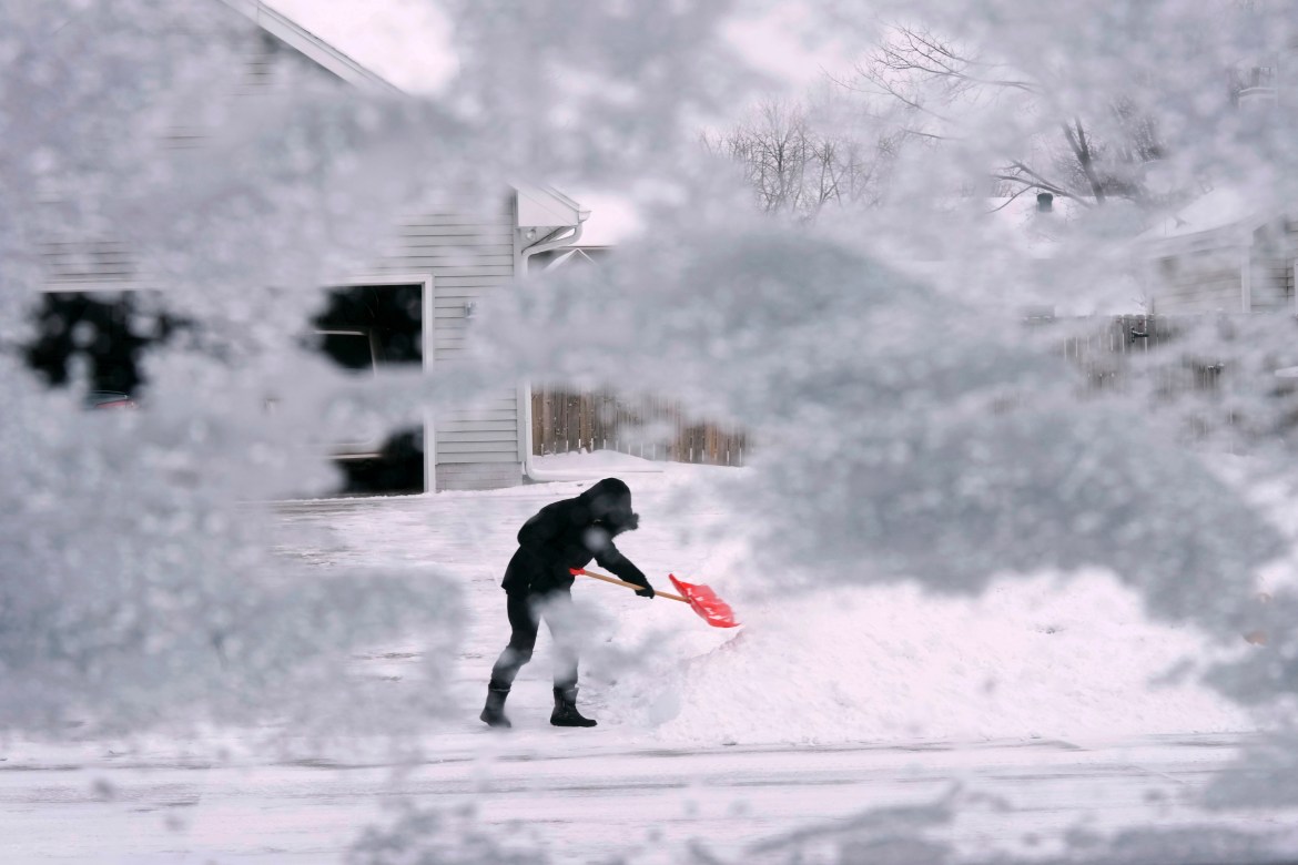 A local resident shovels snow off the end of a driveway