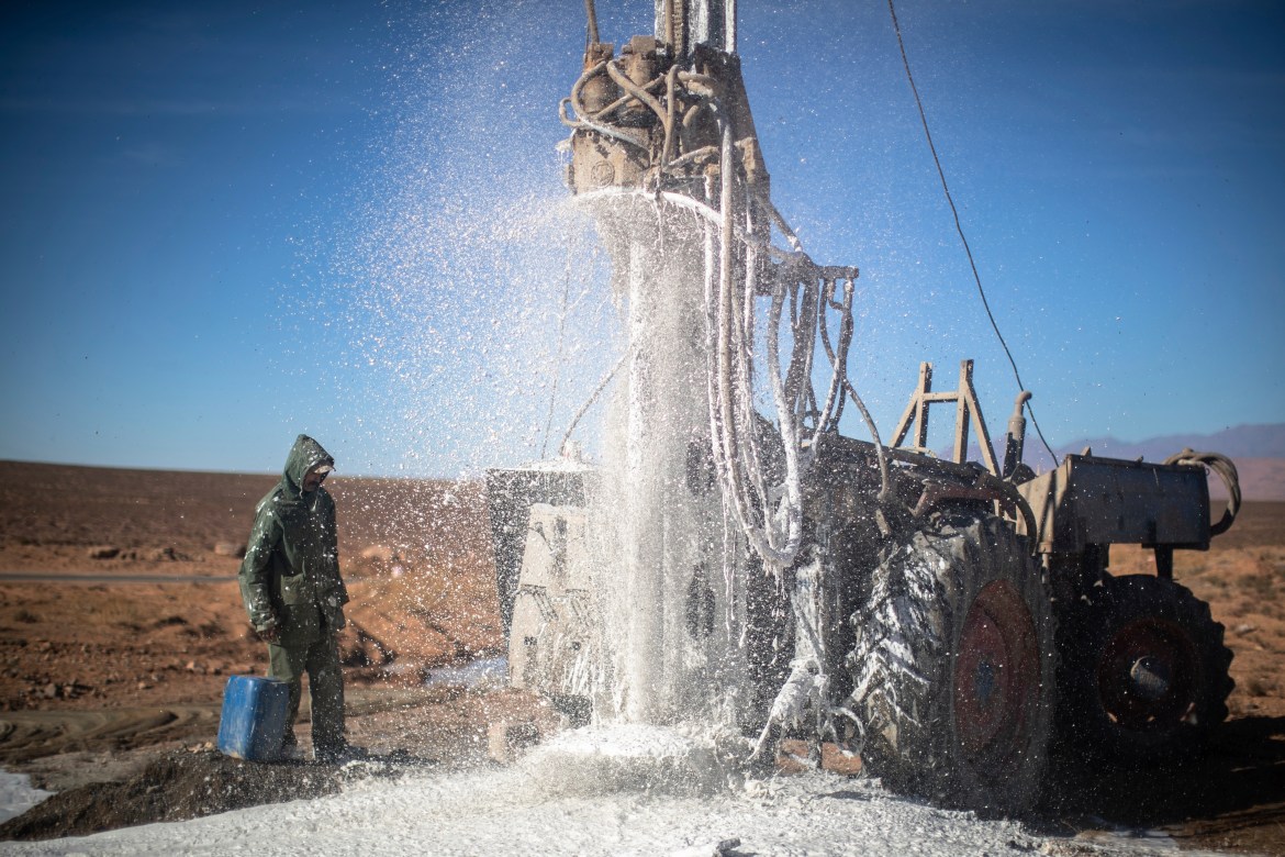 A worker watches as water flows from the ground during a well dig