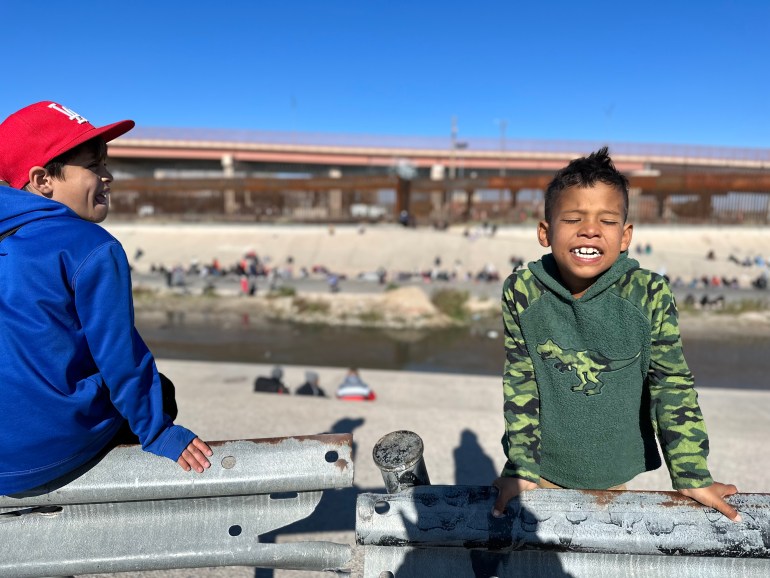 Two brothers smile on the banks of the Rio Grande river.