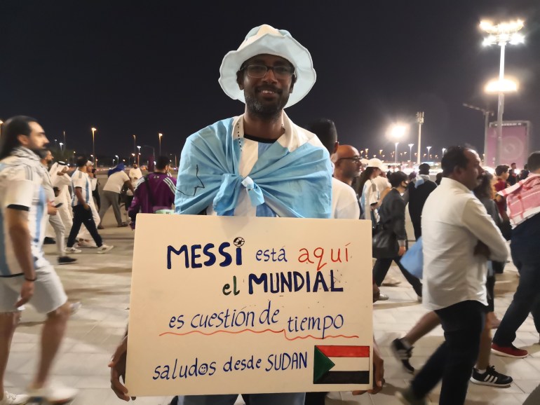 Yasin, from Sudan, holding a placard that says it's only a "matter of time" before Messi and Argentina win the World Cup (Hafsa Adil/Al Jazeera)