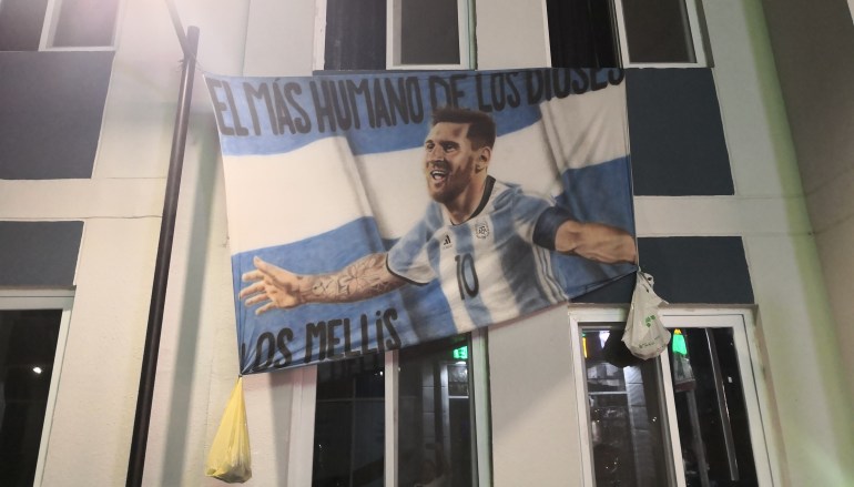A large banner featuring Argentina's Lionel Messi hangs from an apartment in Barahat Al Janoub, or Barwargento, where Argentina supporter are staying in the south of Qatar [Hafsa Adil/Al Jazeera]