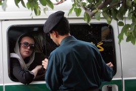 An Iranian policeman speaks with a woman in a police car after she was arrested because of her &#39;inappropriate&#39; clothes [File: Behrouz Mehri/AFP]