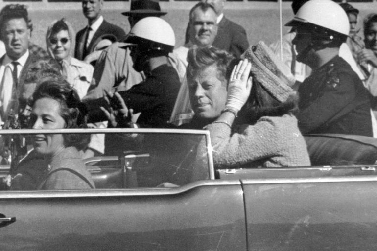 President John F Kennedy waves from his motorcade about one minute before he was shot in Dallas, Texas