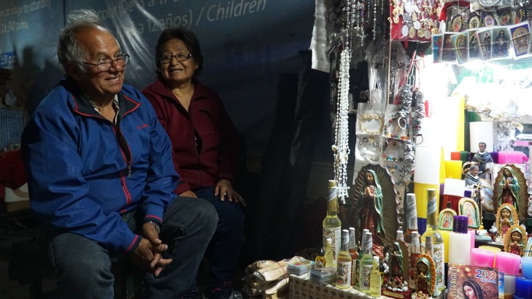 Husband and wife, Raul Room and Juana de la Cruz, sell religious items out of a stand in front of Lima’s Santo Domingo Church