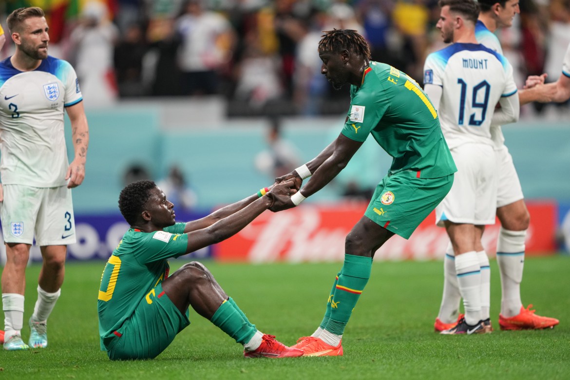 A Senegal player helps one of his teammates up after the final whistle.