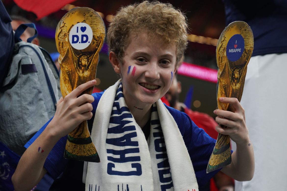 An excited, young France supporter holds trophies