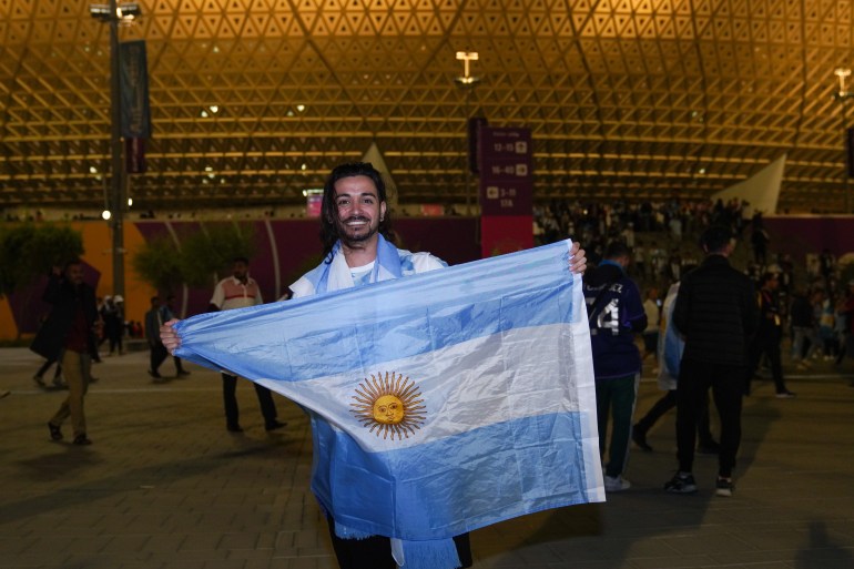 Cristian Rolero holding an Argentinian flag outside the stadium after the match between Argentina and Croatia.