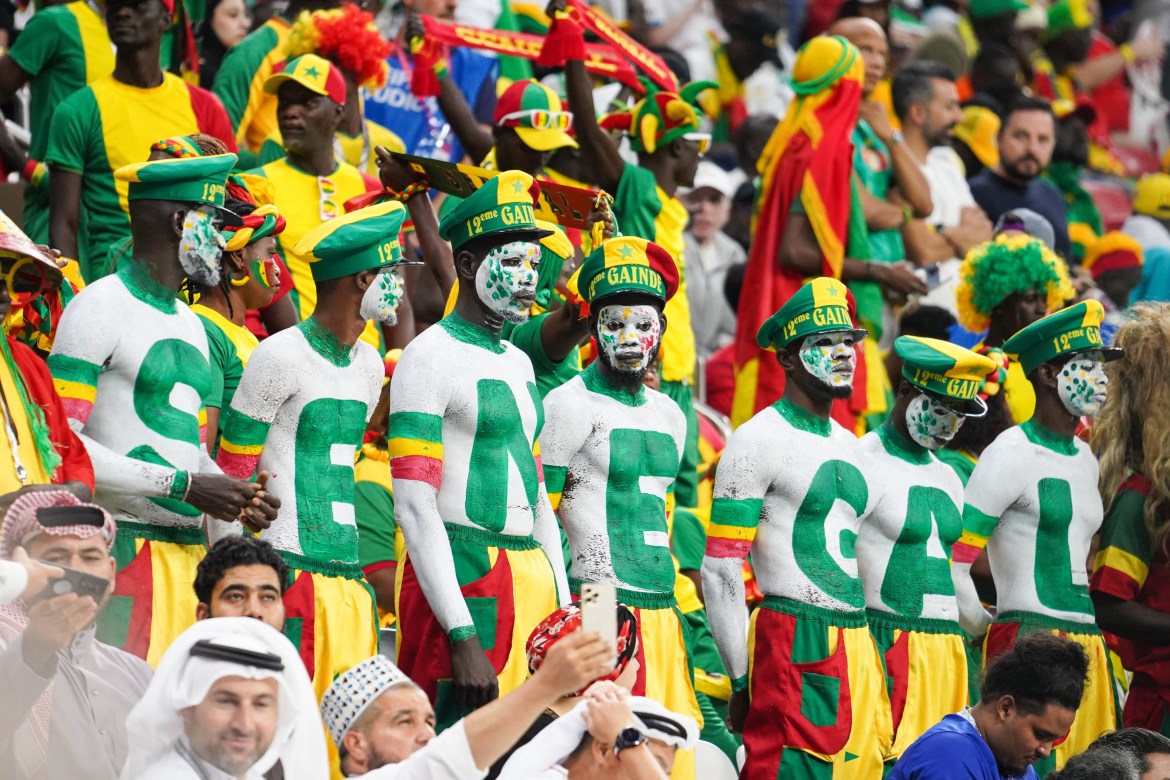 Painted Senegal fans in the stands. The seven fans' body-paint spells the seven letters of the country's name, Senegal.
