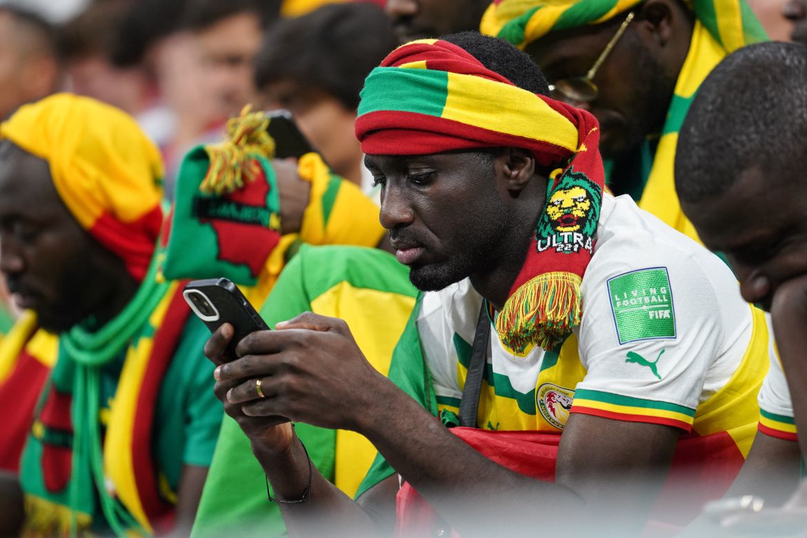 Saddened Senegal fan in the stands looking at his phone.