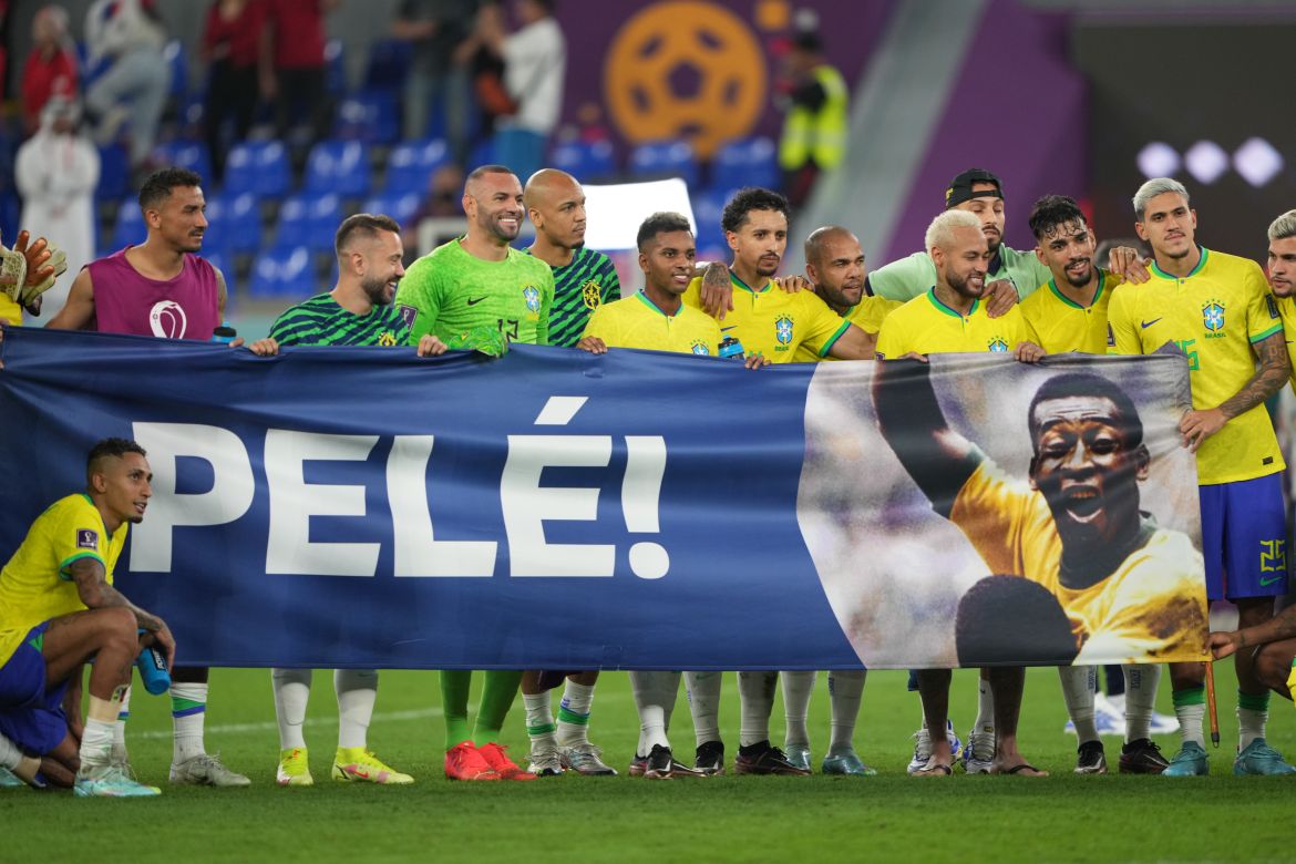 Brazilian players holding a large banner to honour Brazilian legend Pele with the football giant's name, Pele, written in big letters next to a photo of the star.