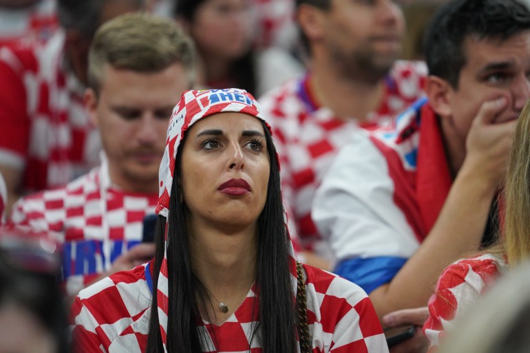 Saddened Croatia fans in the stands. One holds his hand over his mouth