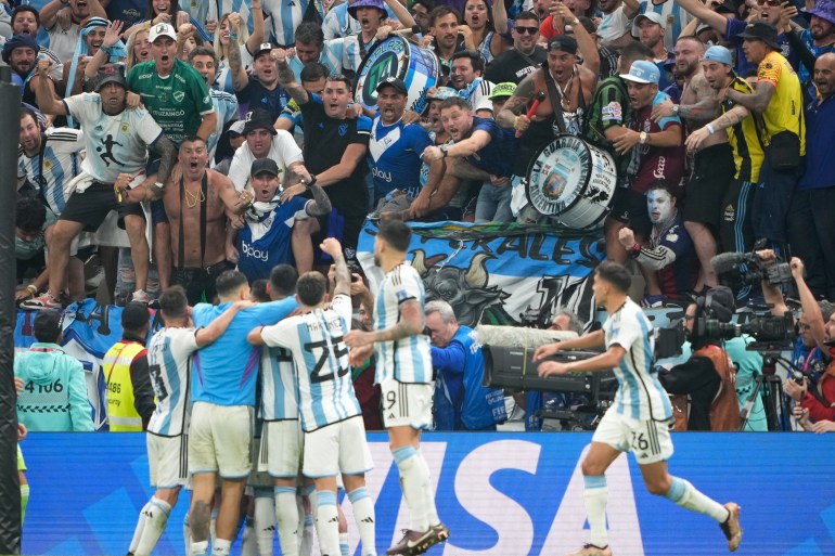 Les supporters argentins crient de joie envers leurs joueurs après que l'Argentine ait marqué son troisième but du match.