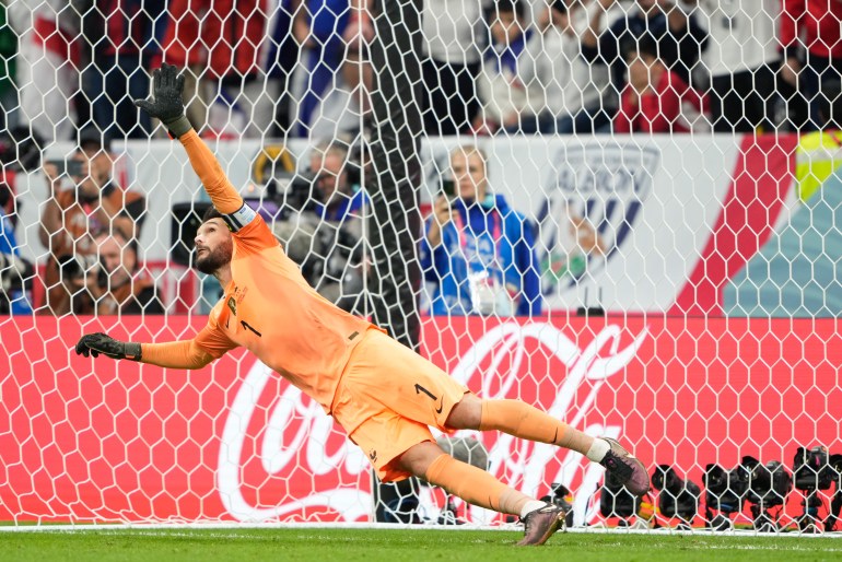 France goalkeeper Hugo Lloris, falling to his right, watches Harry Kane's penalty pass over the net at Qatar's Al Bayt Stadium.