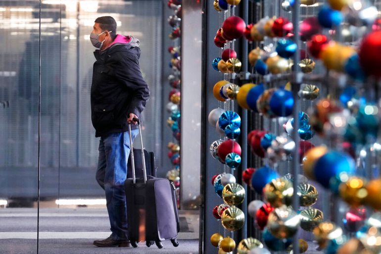 A traveler waits in an airport with holiday ornaments in the background