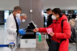 A passenger gives his passport to a worker, after Italy has ordered coronavirus disease (COVID-19) antigen swabs and virus sequencing for all travellers coming from China