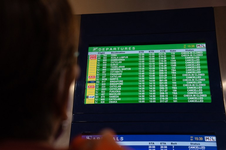 Passengers look at a flight information screen at Terminal 3 of Ninoy Aquino International Airport in Pasay, Metro Manila on January 1, 2023. - Thousands of travelers were stranded at Philippine airports on January 1 after a "loss of communication" at the country's busiest hub, Manila, hundreds of flights had to be cancelled, delayed or diverted.  (Photo by KEVIN TRISTAN ESPIRITU/AFP)