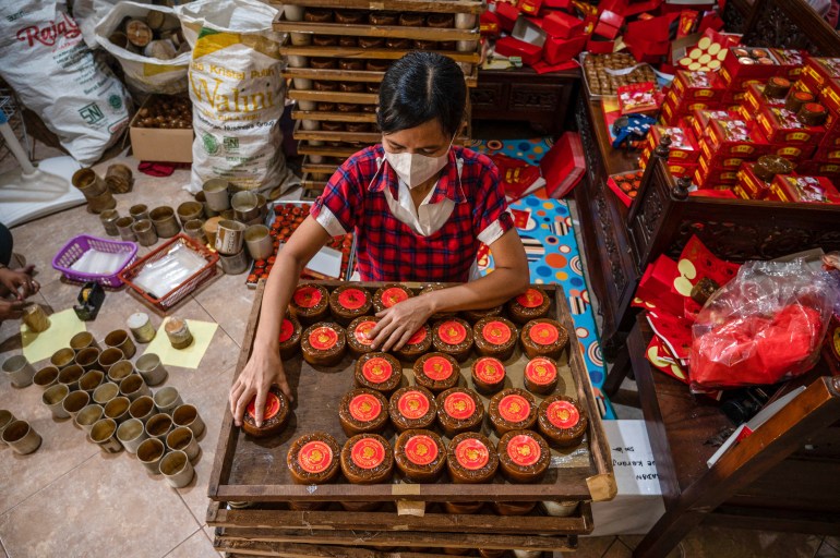 Traditional cakes being prepared in Jakarta. They are on a tray with red tops 