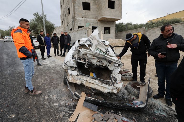 Onlookers surround a bullet-riddled car in which 2 Palestinians were reportedly killed by Israeli troops in Jaba near the West Bank town of Jenin, on January 14, 2023.