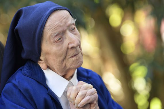 Lucile Randon who became a nun in 1944 and has died at the age of 118. She is wearing a nun's habit in blue and has her hands clasped together.