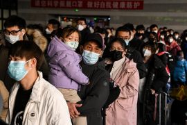 A man holding a child is among passengers queued up at the Beijing West railway station ahead of the Lunar New Year in Beijing, China.