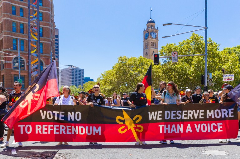 İnsanlar yıllık olarak yer alırken bir pankart tutuyorlar. "İstila Günü" Sidney'de protesto yürüyüşü