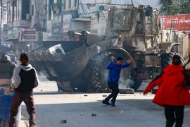Palestinians hurl rocks at an Israeli army bulldozer during confrontations in the occupied-West Bank city of Jenin, on January 26, 2023 [Zain Jaafar/AFP]