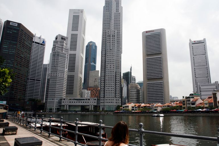 A woman sits looking at the skyline of Singapore's financial district.