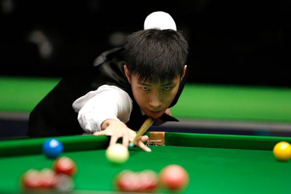 Chinese snooker player Zhao Xintong prepares to take a shot at the table