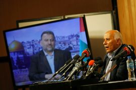 Senior Fatah official Jibril Rajoub speaks in Ramallah in the West Bank in 2020 as deputy Hamas chief Saleh al-Arouri appears on a television screen during a video conference to discuss Israel&#39;s plan to annex parts of the Israeli-occupied West Bank (File: Mohamad Torokman/Reuters)