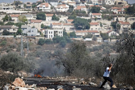 A Palestinian demonstrator hurls stones at Israeli troops as the Jewish settlement of Kedumim is seen in the background, in Kafr Qaddum town in the Israeli-occupied West Bank September 18, 2020.