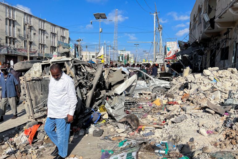 A man walks past wreckage from a bombing in Moghadishu