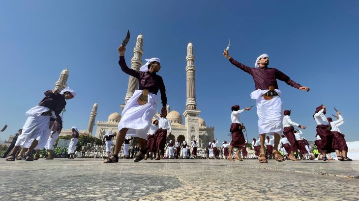 Yemeni men dance with traditional daggers in front of a mosque in Sanaa