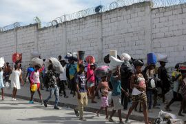 People displaced by gang violence in Port-au-Prince, Haiti, walk while carrying belongings on the streets of the Delmas commune of the city.