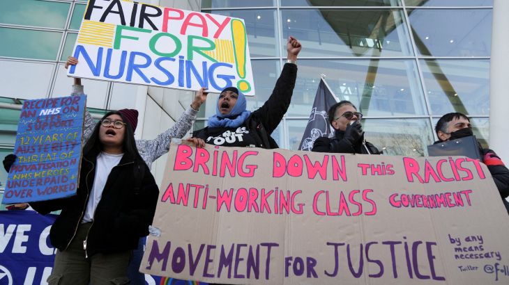 People hold signs outside University College Hospital as NHS nurses march during a strike, amid a dispute with the government over pay, in London
