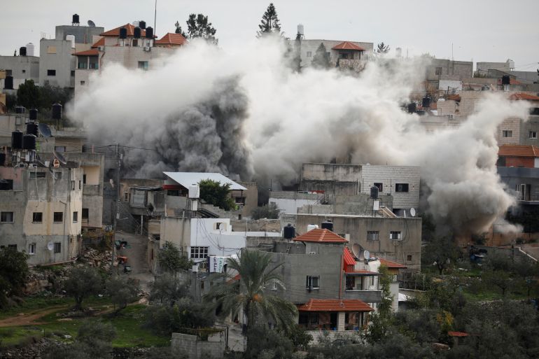 Smoke rising above densely packed residential buildings on a hillside