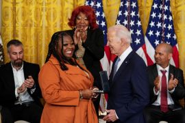 President Joe Biden hands Shaye Moss a medal as her mother applauds
