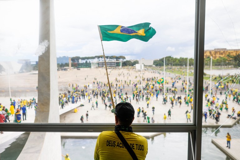 Um homem agita a bandeira do Brasil enquanto apoiadores do ex-presidente Jair Bolsonaro protestam contra o presidente Luiz Inácio Lula da Silva, do lado de fora do Congresso Nacional do Brasil em Brasília