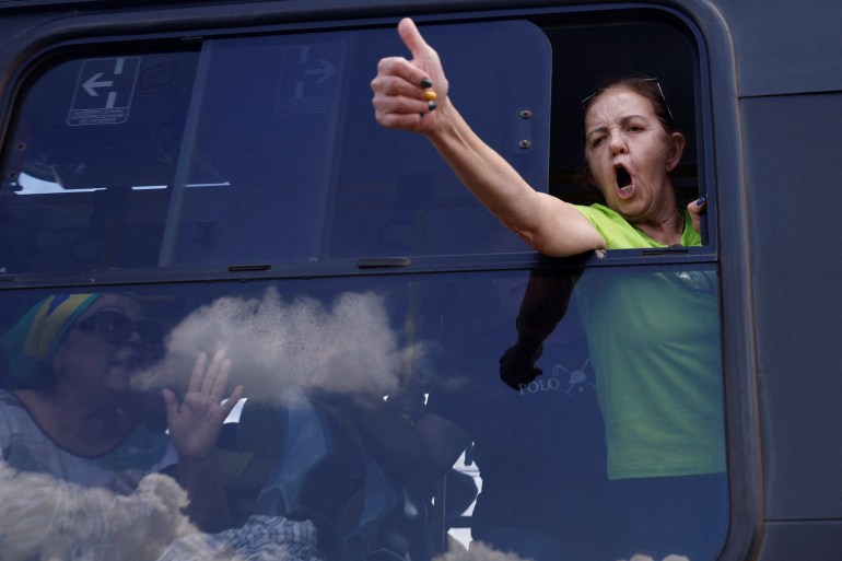 A Bolsonaro supporter gives a thumbs up out the window of a bus