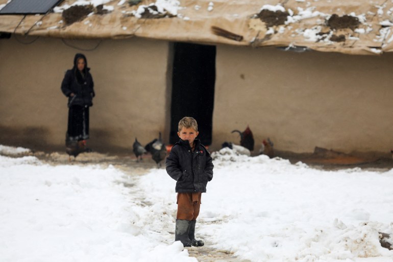An Afghan boy stands on snow-covered ground in Kabul