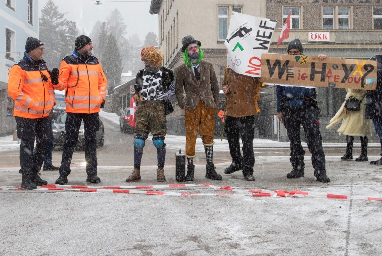 Klimaatactivisten poseren naast Zwitserse politieagenten tijdens een protest voorafgaand aan het World Economic Forum (WEF) 2023 in het Alpenresort Davos, Zwitserland, 15 januari 2023. REUTERS/Arnd Wiegmann