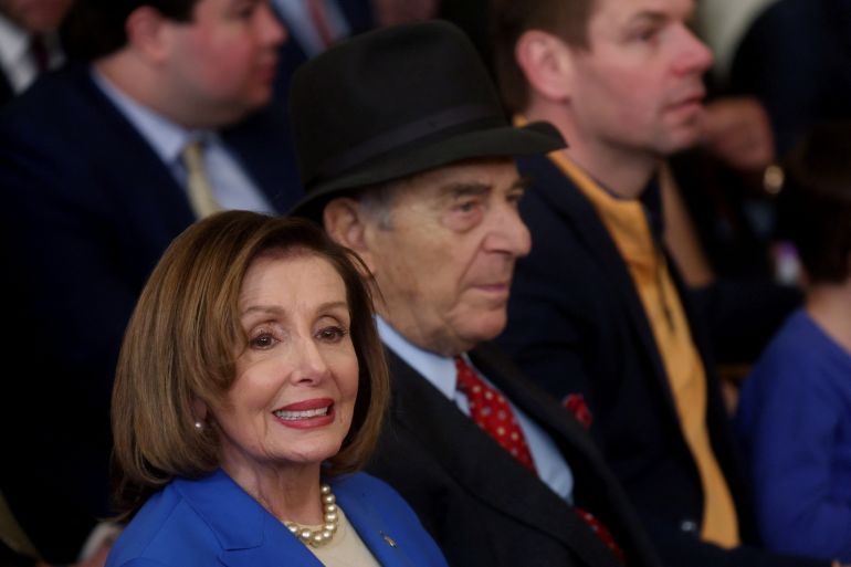 Nancy and Paul Pelosi sit side by side at an event