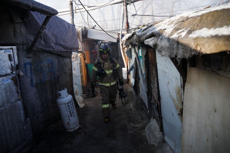 A firefighter walking through a narrow alley between makeshift houses in Guryong on the edge of Seoul's swanky Gangnam district