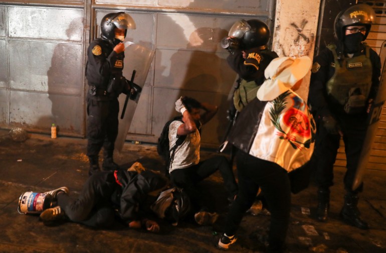 A protester on the ground hides as he is surrounded by riot police during the 'Take over Lima' march to demonstrate against Peruvian President Dina Boluarte, following the ouster and arrest of former President Pedro Castillo, in Lima, Peru January 20, 2023 . 