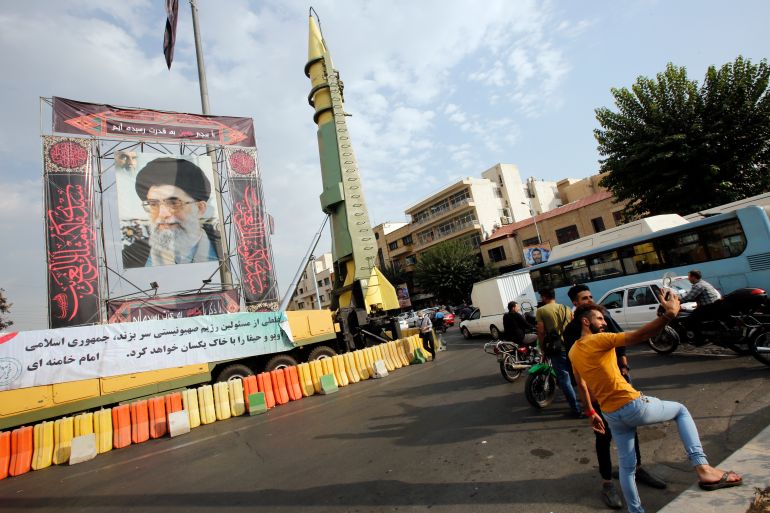 ranians take selfies next to a picture of Iranian supreme leader Ayatollah Ali Khamenei