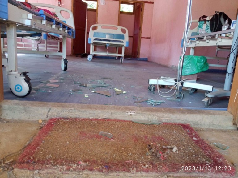 Hospital beds in a room with broken glass and some debris on the floor after an air strike