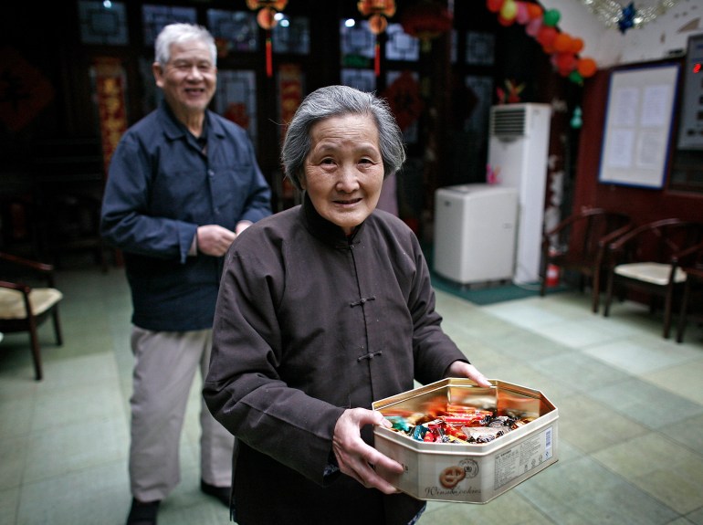 An elderly woman distributes goodies to visitors at the Fengyiyuan, a government-funded nursing home in downtown Beijing, Friday, March 19, 2010. China's ratio of 16 elderly people per 100 workers is set to double by 2025, then double again to 61 by 2050, due partly to family planning policies that limit most families to a single child, a U.S. study said. (AP Photo/Andy Wong)