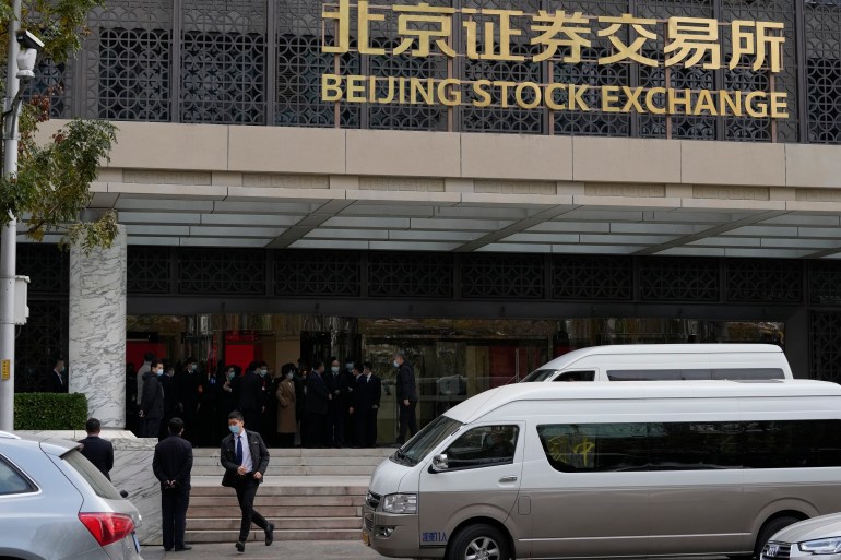 Un homme court devant la Bourse de Pékin qui a ouvert ses portes à Pékin le lundi 15 novembre 2021. Une bourse créée dans la capitale chinoise pour servir les entrepreneurs a ouvert ses portes lundi avec 81 entreprises dans le cadre d'une répression contre les géants de la technologie du pays qui a anéanti plus de 1 billion de dollars de moins que leur valeur marchande à l'étranger.  (AP Photo/Ng Han Guan)